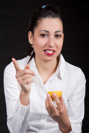 Woman holding in hands yellow lemon and have a raised fingerの写真素材