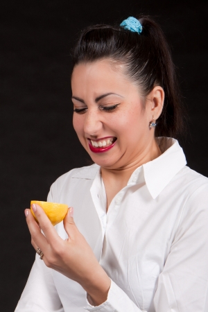 Woman holding in hands yellow lemon and makes a grimaceの写真素材
