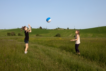 Two teen girls are throwing a beach ball on the meadowの写真素材