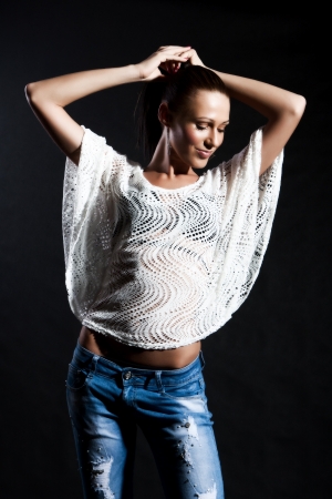Woman with long hair in a netted shirt and jeans has closed eyes on a black backgroundの写真素材