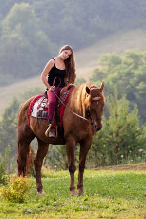 Young girl with long hair sitting on a horse breed Quarter Horseの写真素材