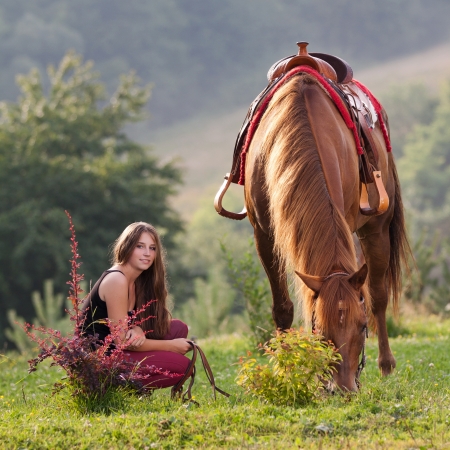 Young girl with long hair is squatting next horse breed Quarter Horseの写真素材
