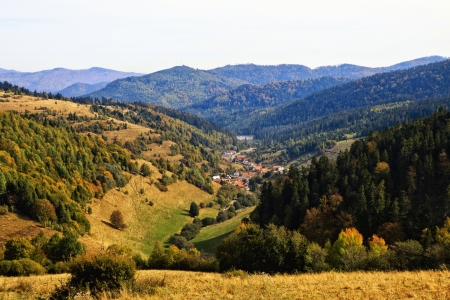 Autumn valley with hills and sky and village in the valleyの写真素材