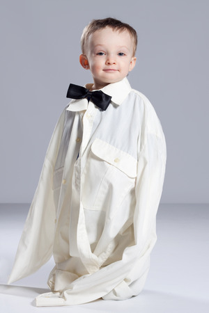 Boy toddler businessman, standing dressed in grown-shirt with bow tieの写真素材