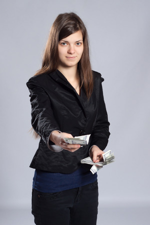 Young long-haired woman holding dollars and offered moneyの写真素材