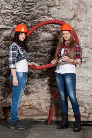 Two young long-haired woman looking cables for the repair of an old houseの写真素材