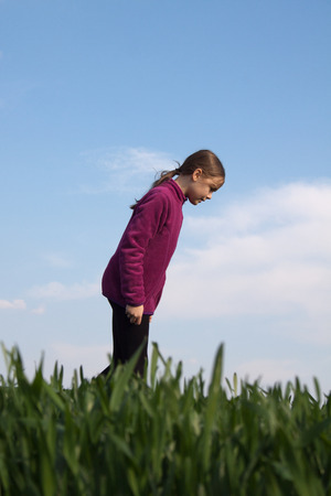Young girl searches for something on the grassの写真素材