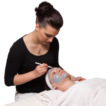 Beautician applied a young woman cosmetic facial mask with a brushの写真素材