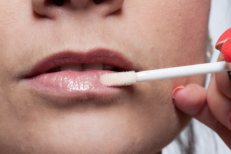 Detail application of gloss using the applicator on female lipsの写真素材