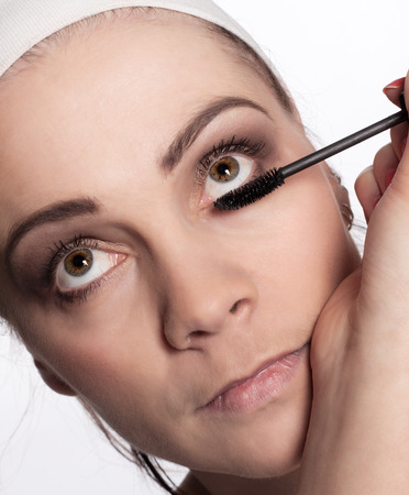 Beauticians paints using mascara eyelashes young brunette woman with headband on her headの写真素材
