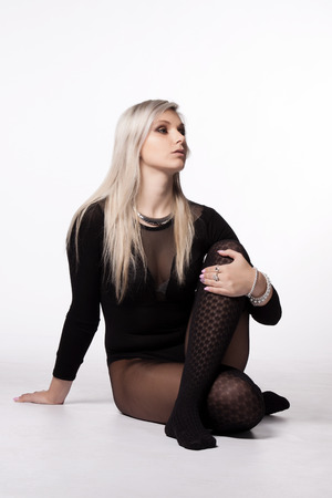 Attractive young long-haired blond woman in lingerie, and extravagant nylons posing in studioの写真素材