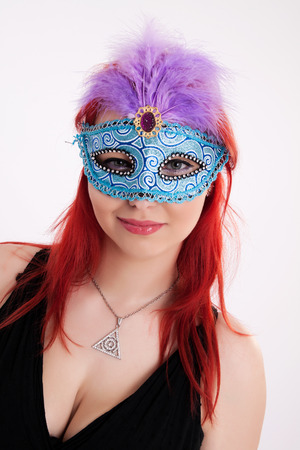 Portrait of young plump red-haired woman with carnival mask on her faceの写真素材