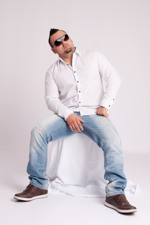 Young businessman in white shirt sits and thinksの写真素材