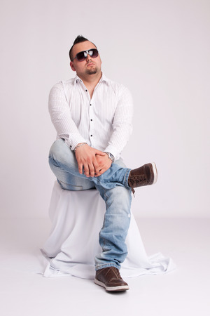 Young businessman in white shirt sits and thinksの写真素材