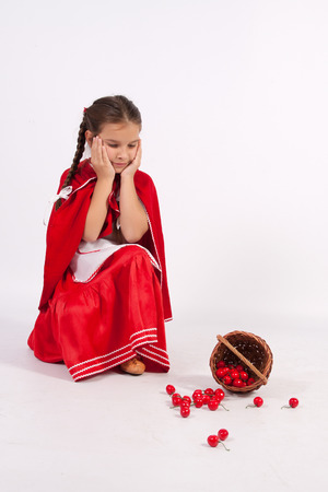 Girl in costume of red cap with spilled cherry,の写真素材
