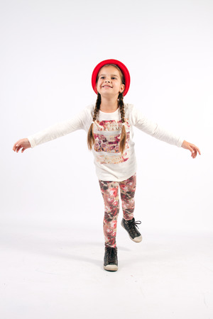Little girl dance with a red hat with outstretched armsの写真素材