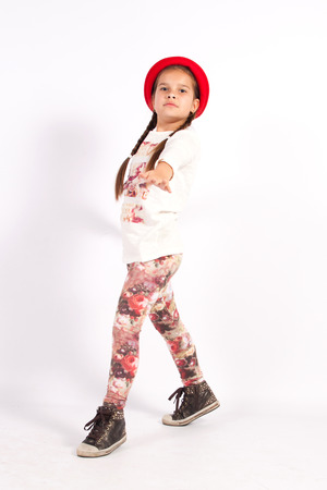 Little girl dancing with a red hat with hands on each otherの写真素材