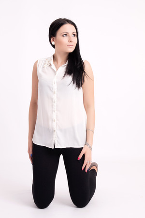 Young long-haired black-haired woman kneeling thoughtfulの写真素材