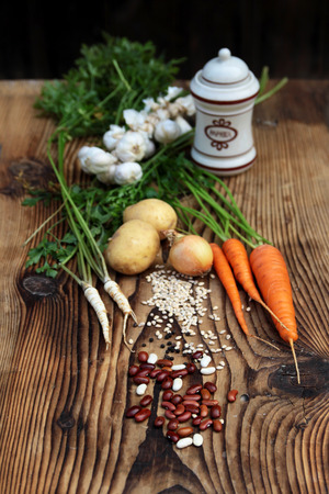 Beans, carrots, parsley, onions, potatoes and paprika on old traditional wooden boardの写真素材