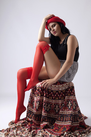 Young long-haired woman with red hat sitting thoughtfully on chairの写真素材