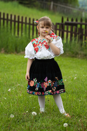 Little girl in traditional costume holding a dandelion in handの写真素材