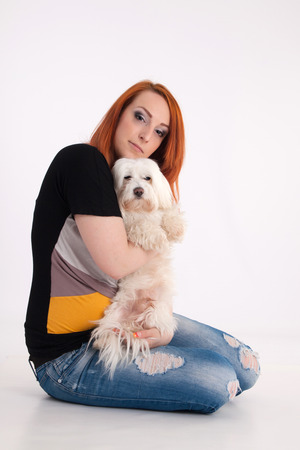 Young redhead woman with her white Maltese dog in studioの写真素材