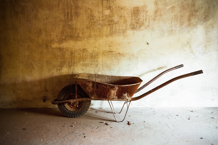 An old rusty metal wheelbarrow in a roomの写真素材