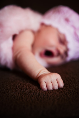 a newborn baby sleeping in a brown blanketの写真素材