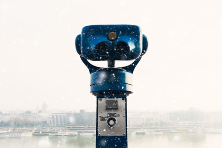 community telescope in a lookout, view onto the city, snowfall