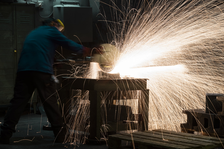 laborer working in a factory grinding machineの写真素材