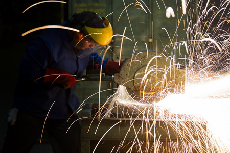 laborer working in a factory grinding machineの写真素材