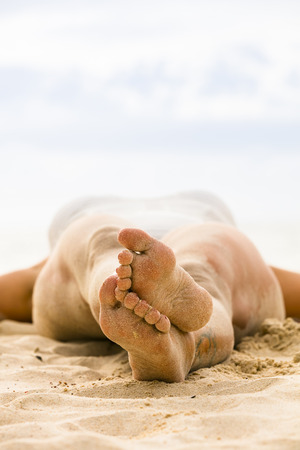 young woman lying on the beach in the sandの写真素材