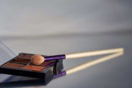 Makeup brush and shadow palette on reflective surface.の写真素材