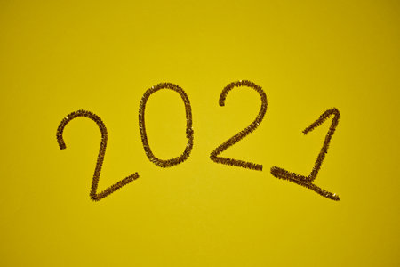 New year 2021 inscription made of glittering tinsel with a yellow background.の写真素材