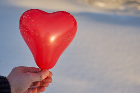 A red ball in the shape of a heart in the hand of a white man. Valentines day concept.