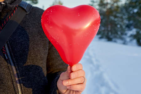 A red ball in the shape of a heart in the hand of a white man. Valentines day concept.の写真素材