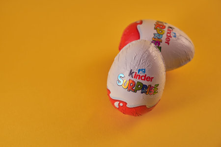 TURKU, FINLAND - FEBRUARY 25, 2021: Kinder Surprise chocolate eggs with a toy on a yellow...