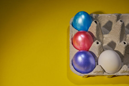 Pearl colored eggs in the egg tray on a yellow background. Easter concept.