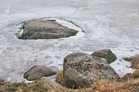 Ice around the stone on the river in early spring.の写真素材
