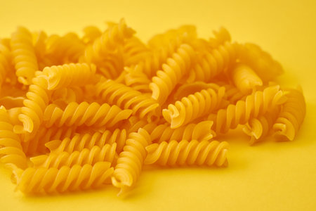 Pasta in the form of spirals on a bright yellow background.