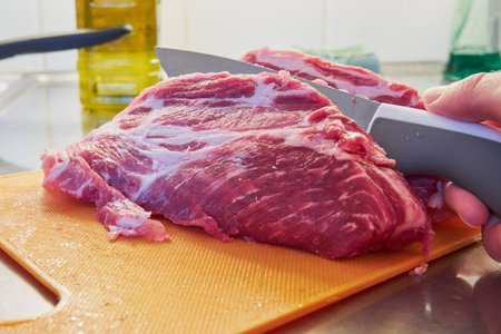 The knife cuts a large piece of meat with a layer of fat.