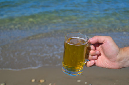 A mug of light beer in the hand of a man.の写真素材