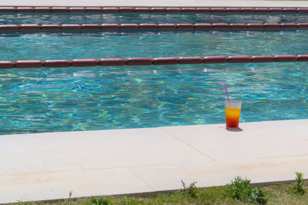 A summer cocktail stands on the edge of the pool.