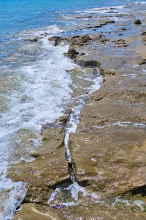 Waves crashing against stones by the seaの写真素材