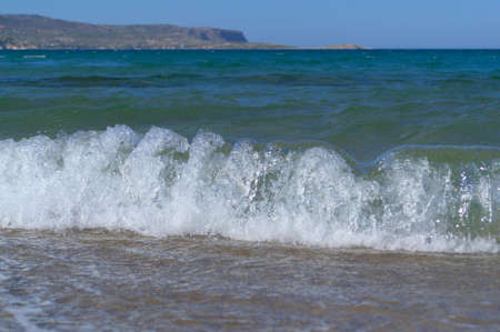 Close-up sea wave with white foam on a sandy tropical beach.の写真素材
