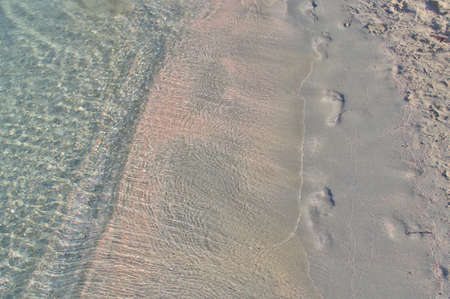 Footprints on a sandy tropical beach with pink sand.の写真素材