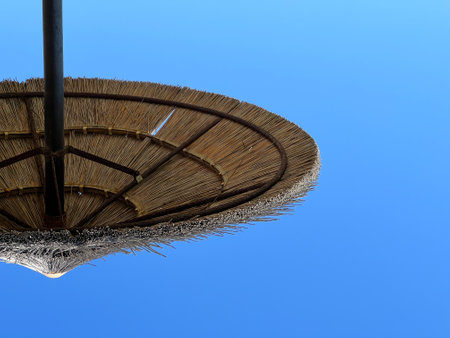 Straw umbrella against the blue sky.の写真素材