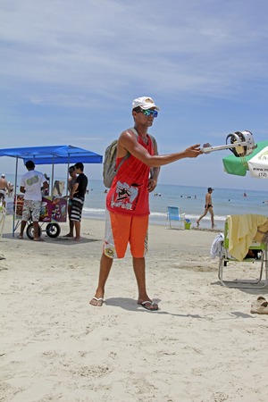 SAO SEBASTIAO, BRAZIL - JANUARY 04, 2015: An unidentified walking vendor with hand-held charcoal oven roasting handmade cheese on a beach in Brazil.のeditorial素材