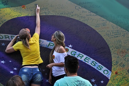 SAO PAULO, BRAZIL August 16, 2015: Two unidentified women  signing a large brazilian flag in the protest against federal government corruption in Sao Paulo Brazil.のeditorial素材