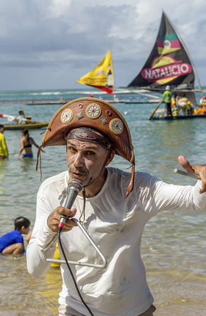 Pernambuco, Brazil July 6, 2016: An unidentified singer in Chicken Beach with typical sail boats behind in Ipojuca City near barrier reef, northeast Brazilのeditorial素材